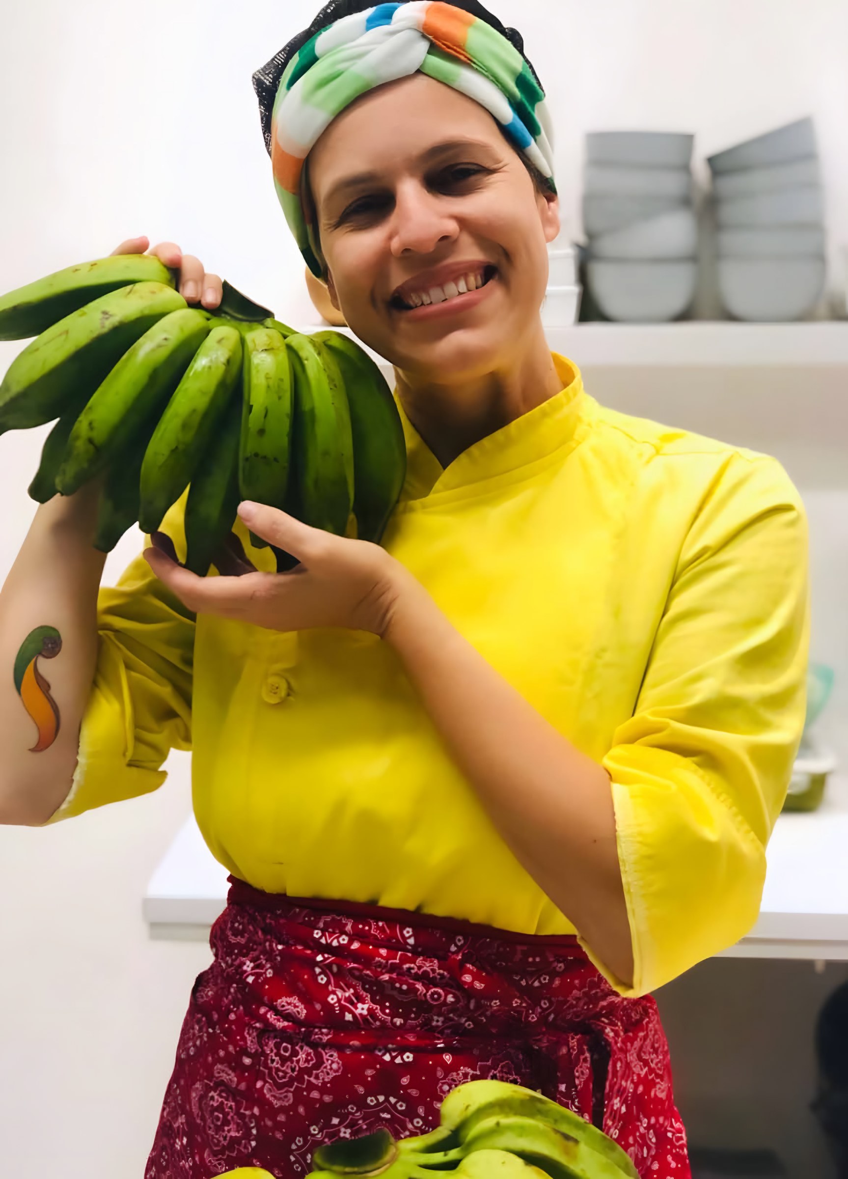 Chef Maia Deva segurando cacho de bananas verdes